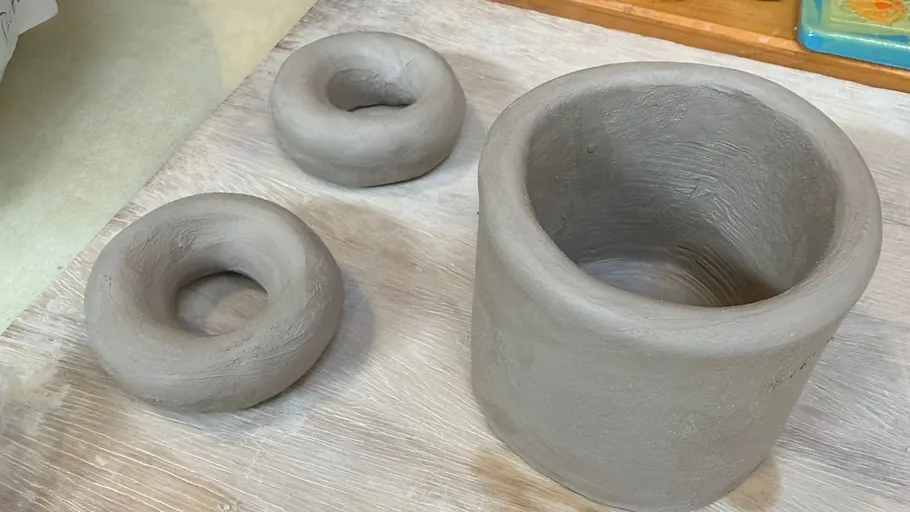 Clay pot and rings on wooden table.