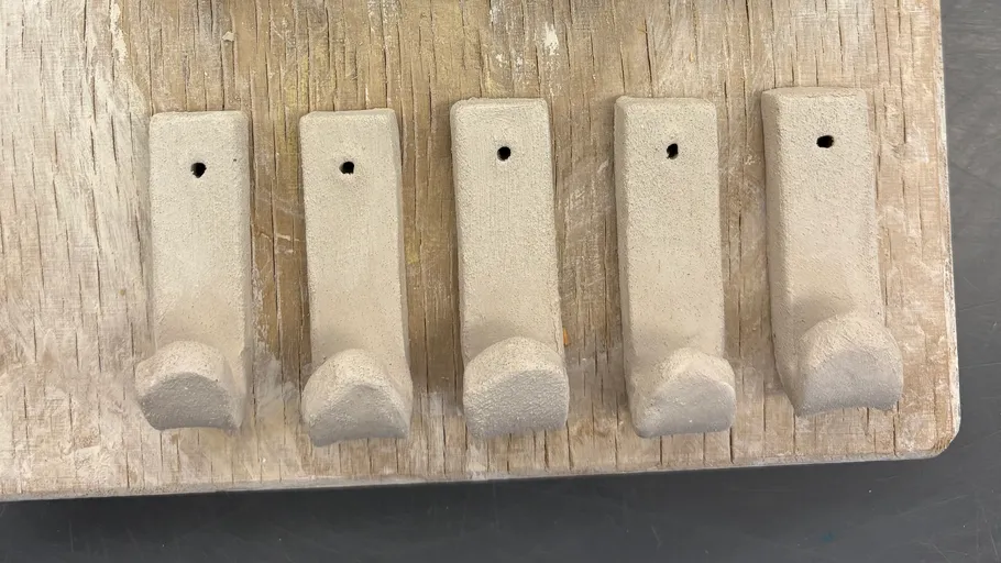 Five clay hooks on wooden board.