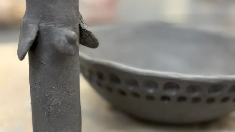 Schwarze Keramikskulptur und Schüssel auf Tisch.