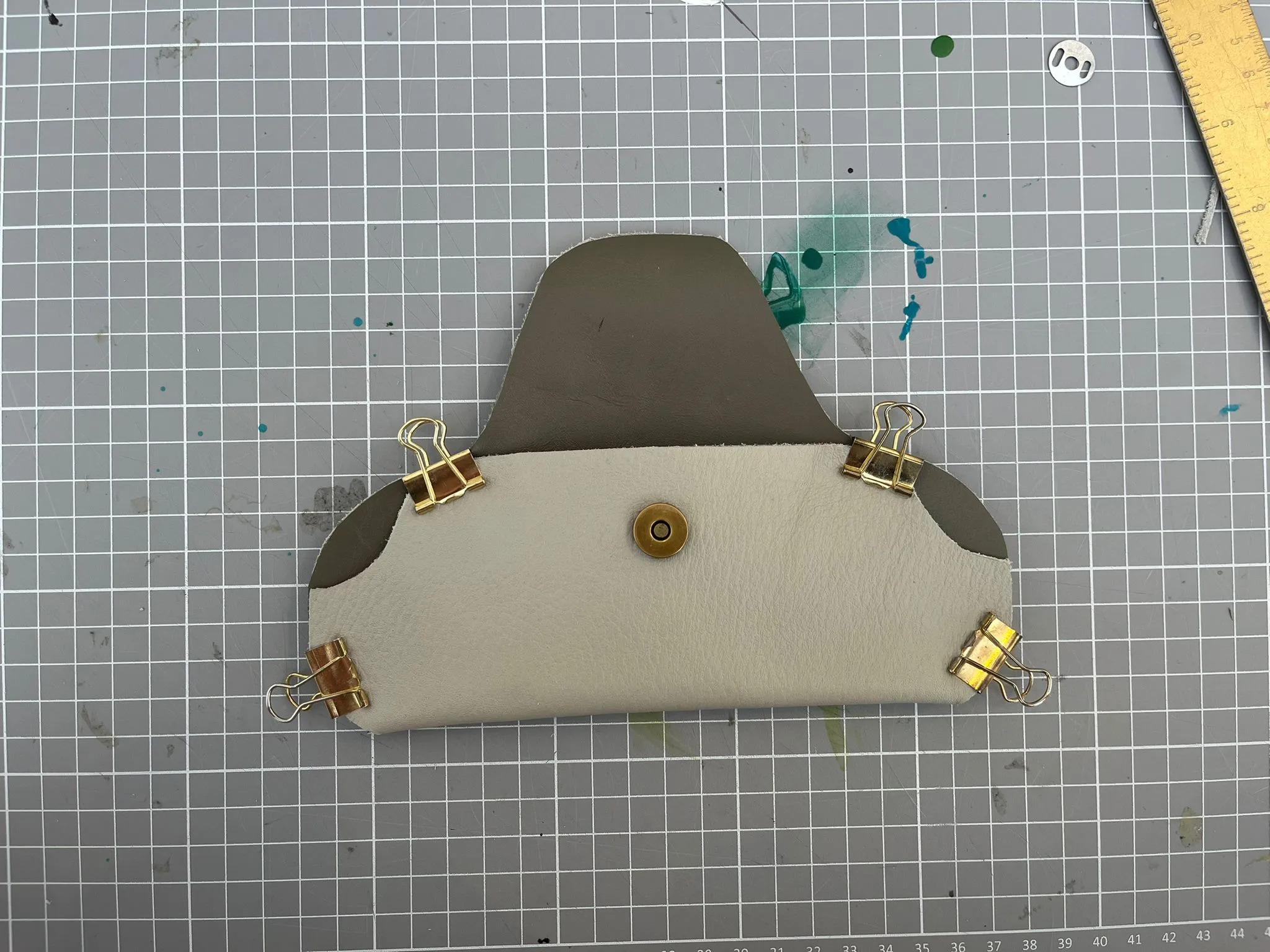 Leather piece clipped and snapped on grid mat.