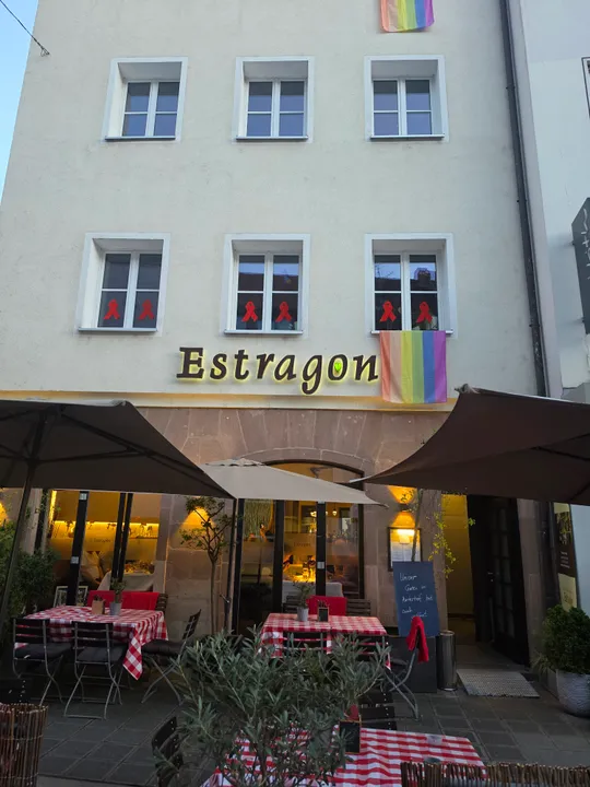 Restaurant mit Außensitzplätzen und Regenbogenflaggen.