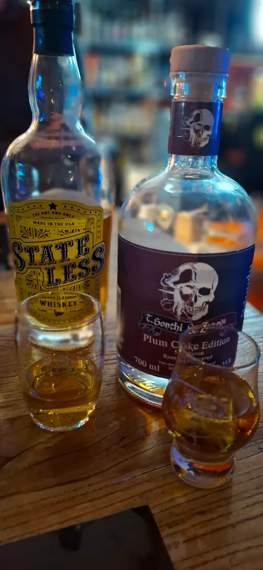 Zwei Whiskyflaschen und Gläser auf Holzfläche.