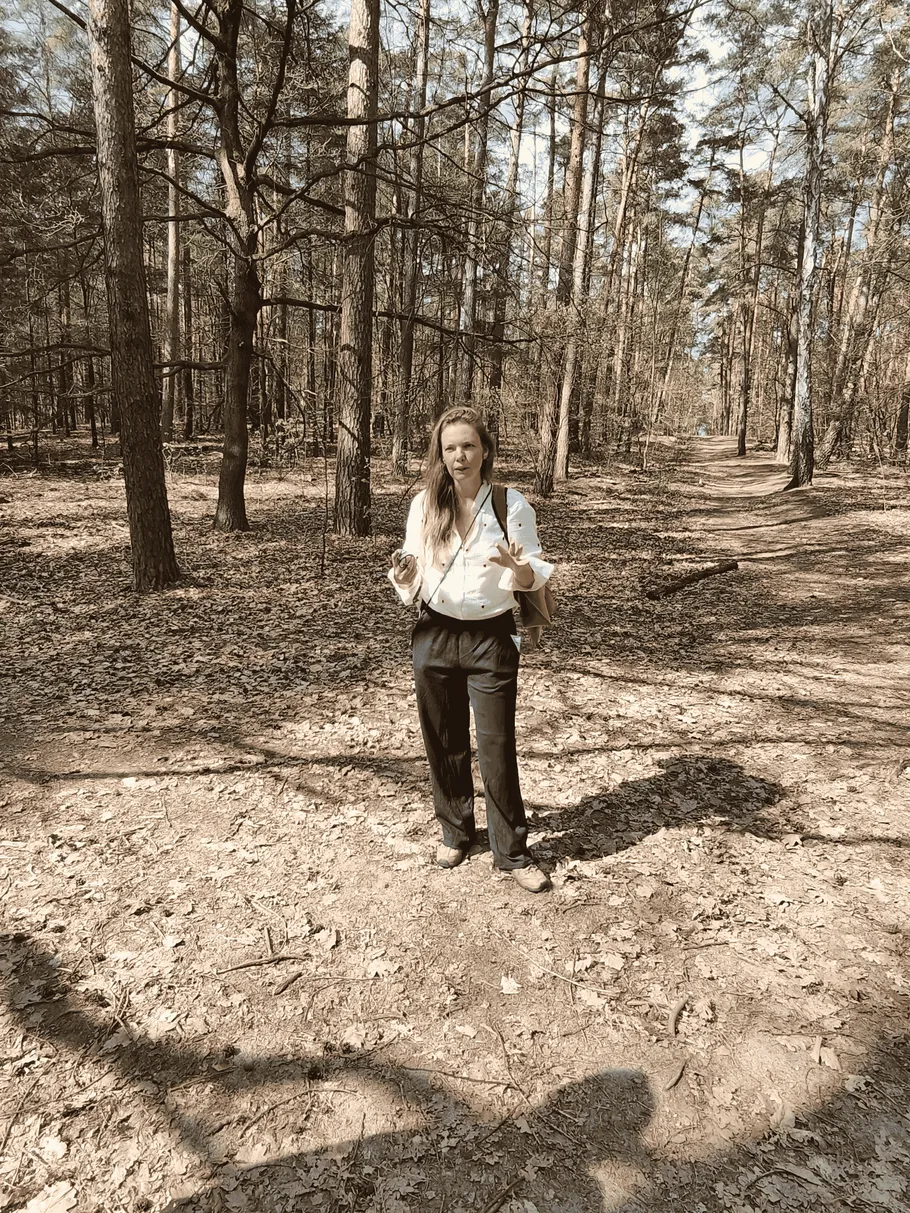 Person standing in a sunlit forest path.