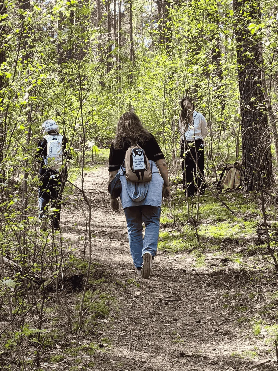People hiking on forest path with backpacks.