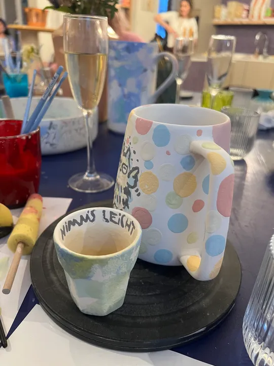 Painted ceramics on a table, glasses around.