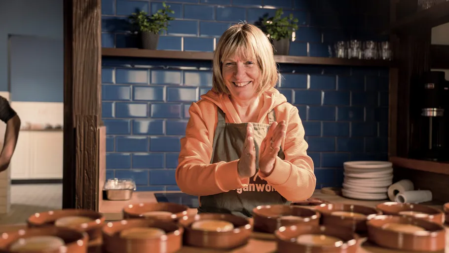 Woman clapping contentedly in a kitchen setting.