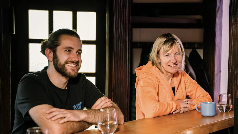 Two people smiling at a wooden counter.