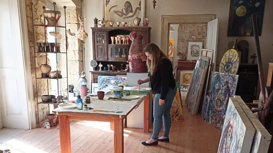 Woman painting in a well-lit art studio.
