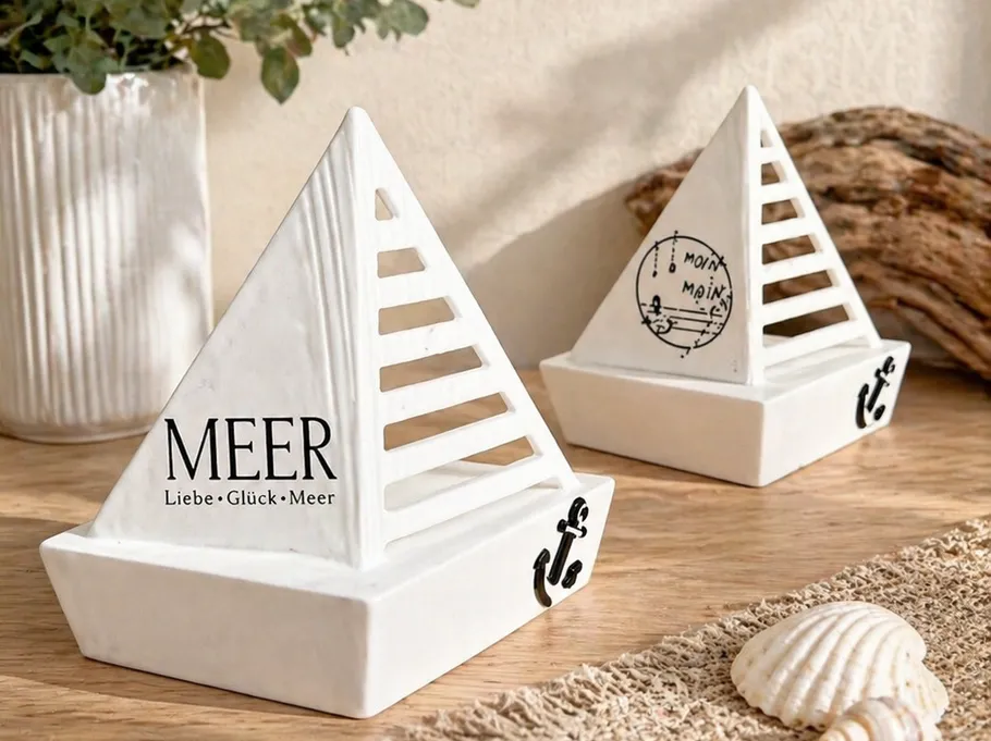 Ceramic sailboat ornaments on wooden table.