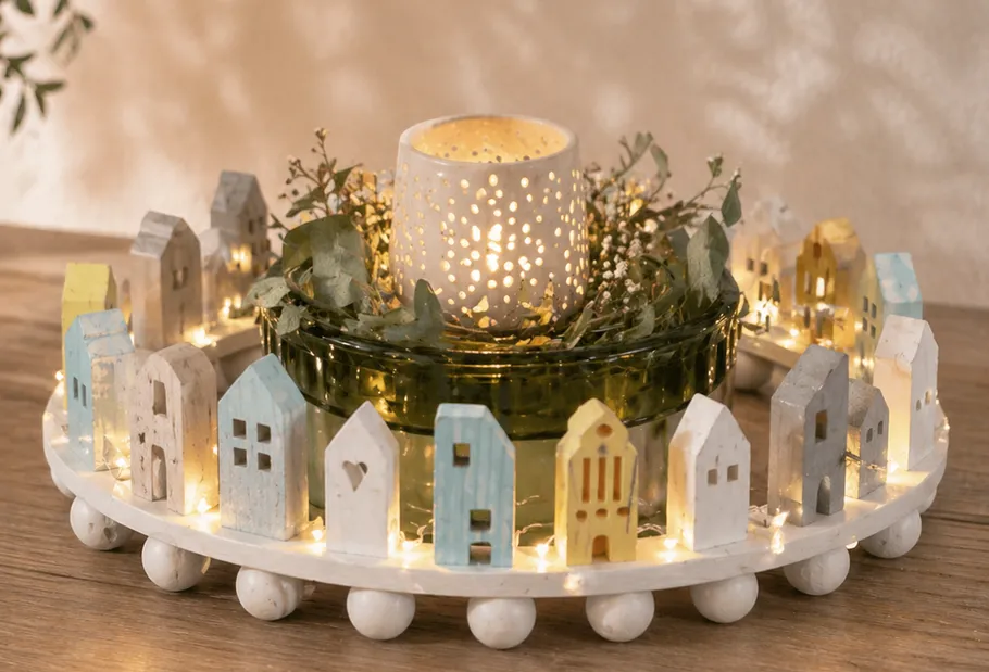 Candle surrounded by wooden houses and lights.
