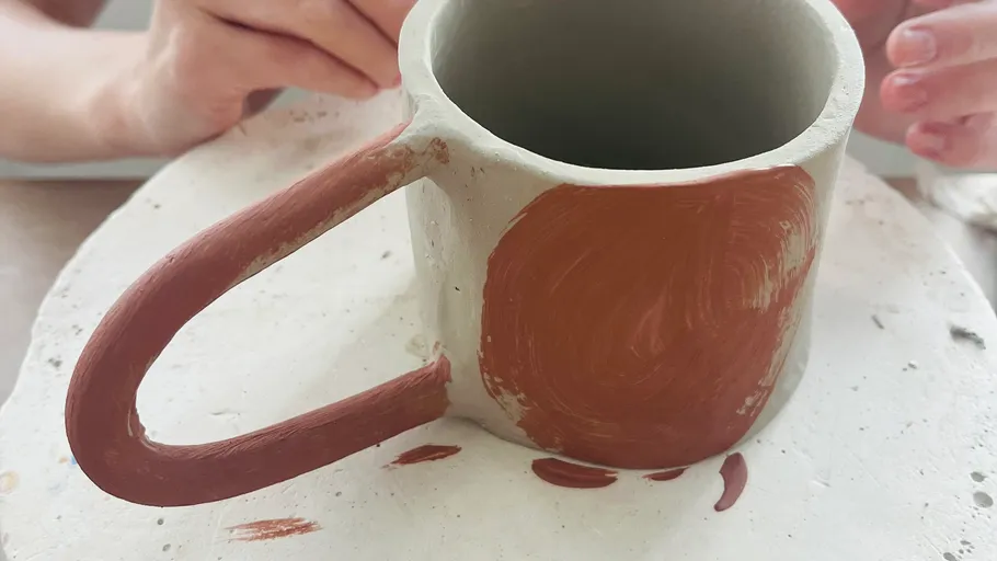 Tontasse wird auf einem Tisch bemalt.