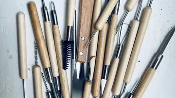 Wood-handled clay sculpting tools scattered randomly.