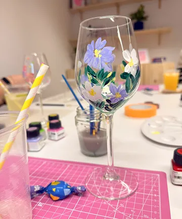 Bemaltes Weinglas mit Blumendesign, Bastelmaterialien.