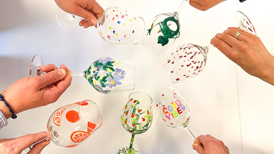 Hands holding decorated wine glasses in a circle.