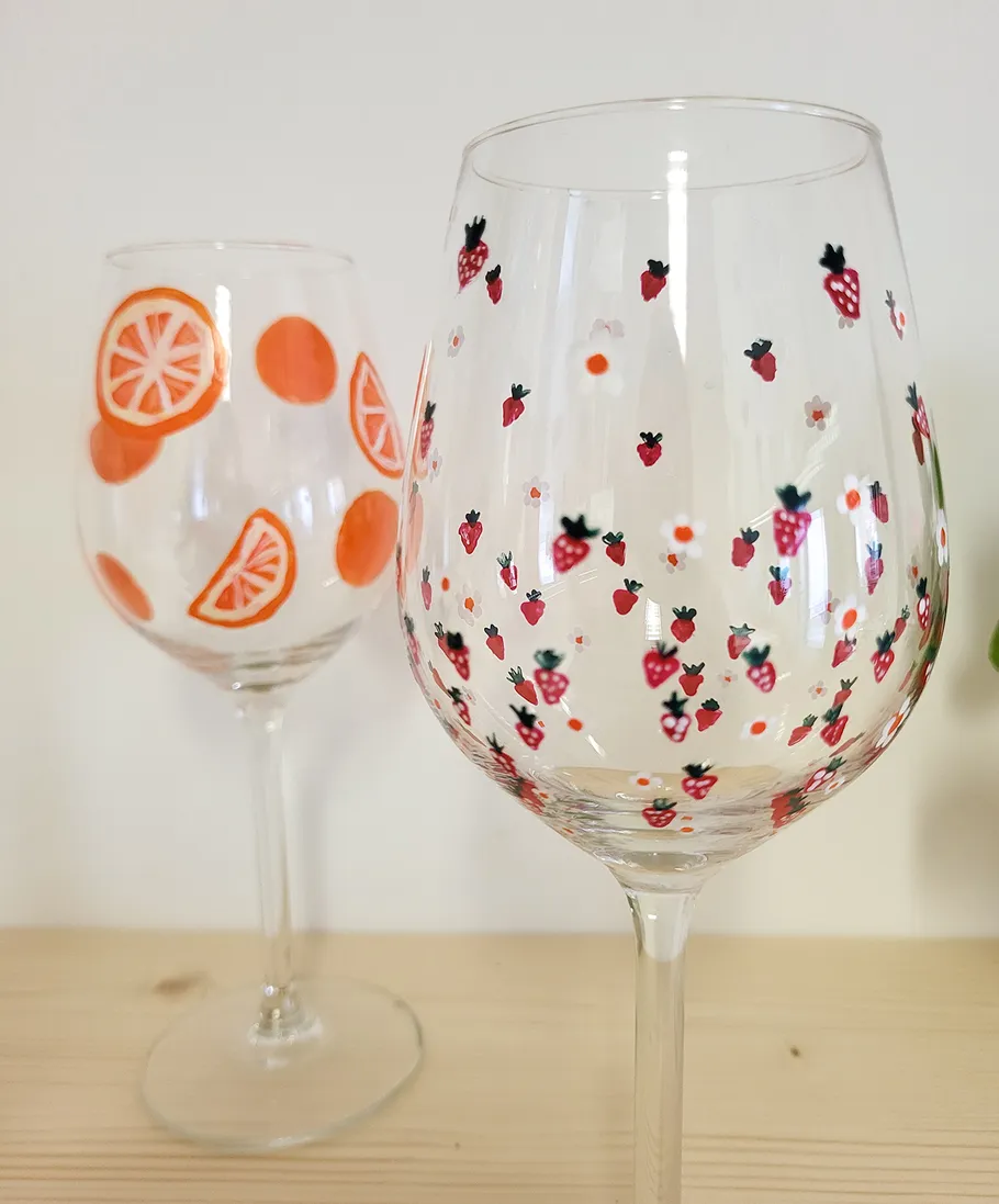 Decorated wine glasses with fruit patterns on table.