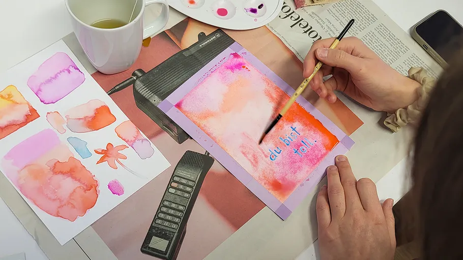 Person painting colorful message at desk.