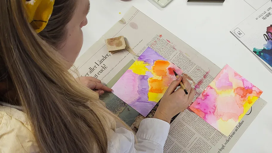 Frau malt abstrakte Aquarellkunst auf Papier.