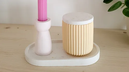 Pink candle and container on wooden tray.