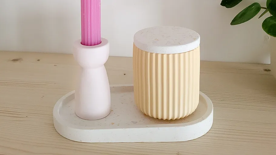 Pink candle and container on wooden tray.