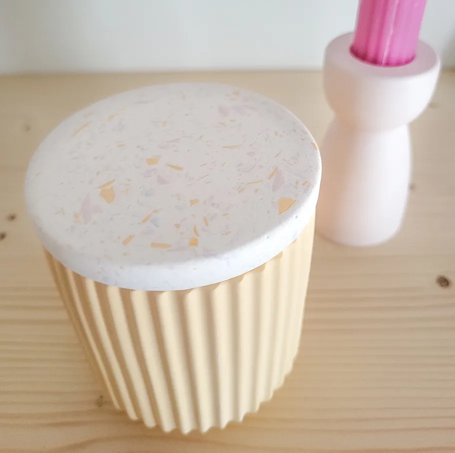 Textured jar and pink candleholder on wood.