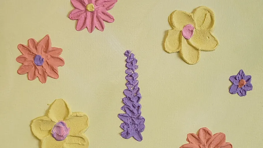 Colorful clay flowers on yellow background.