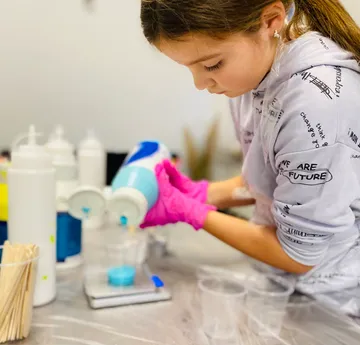 Child pouring liquid with precision in workshop.