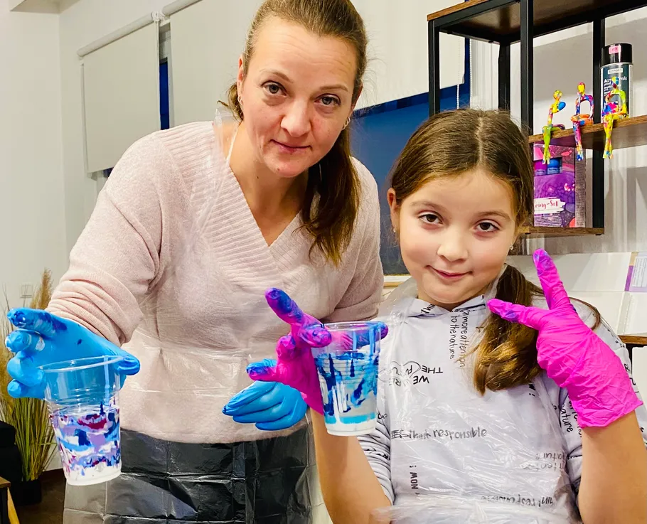 Two people holding painted cups indoors.