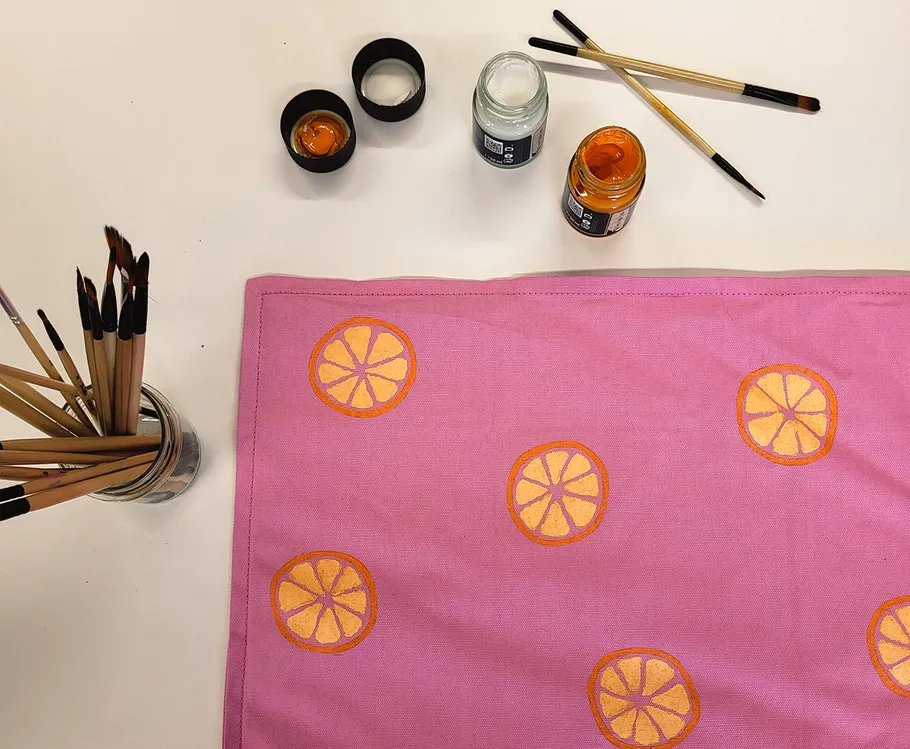 Painted textile with citrus patterns and paint supplies.