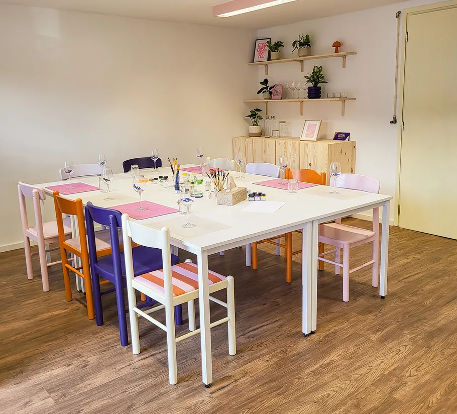 Colorful chairs around table, art supplies present.