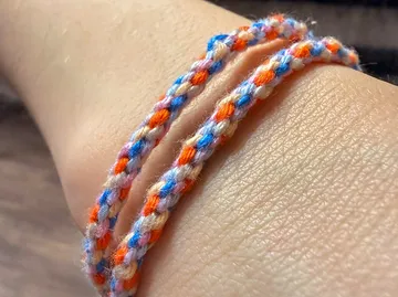 Buntes Armband um ein Handgelenk gewickelt.