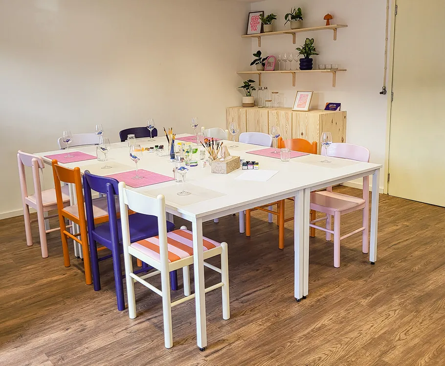 Table set for art class with colorful chairs.