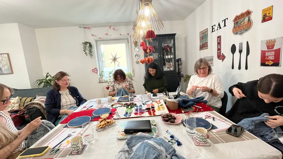 Women sewing and crafting around dining table.