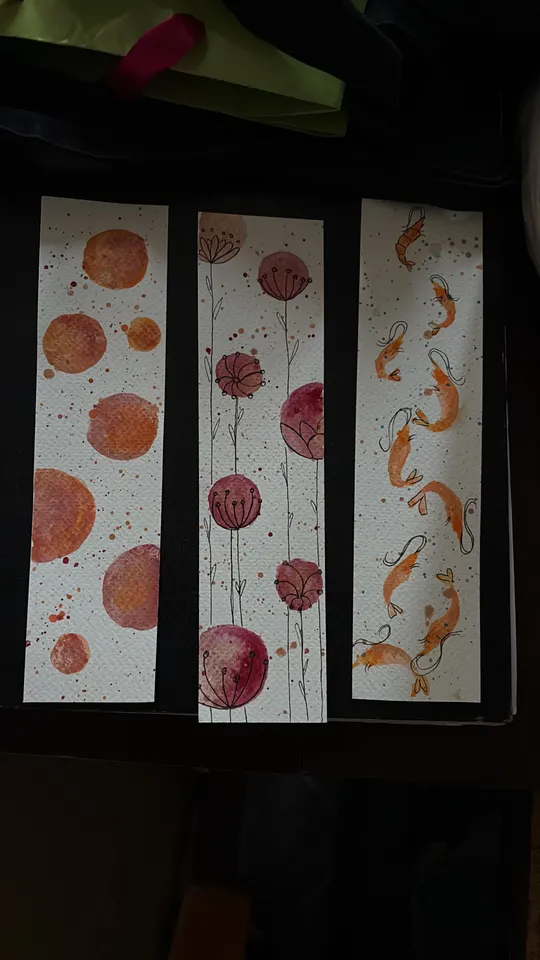 Three watercolor bookmarks with artistic designs.