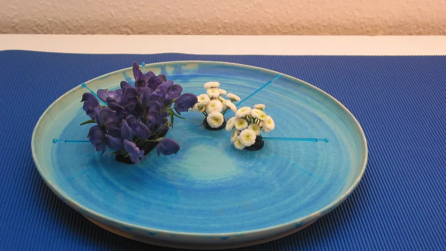 Blumen auf einem blauen Teller mit Zahnstocher.