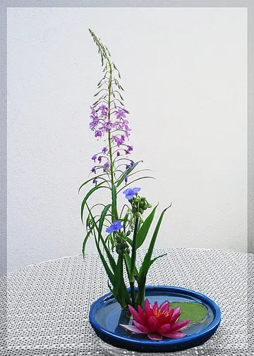 Blumengesteck mit lila Blumen auf Tisch.