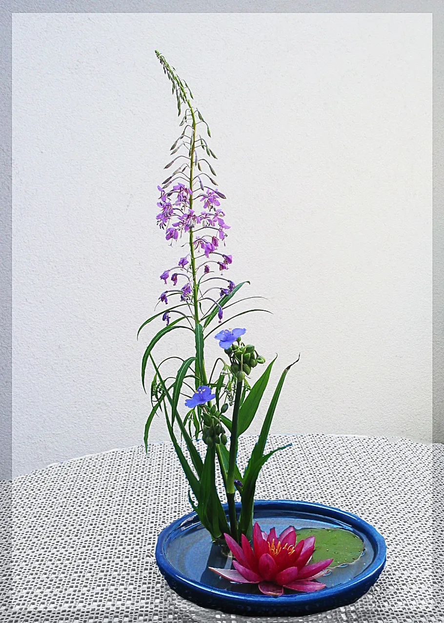 Blumengesteck mit lila Blumen auf Tisch.