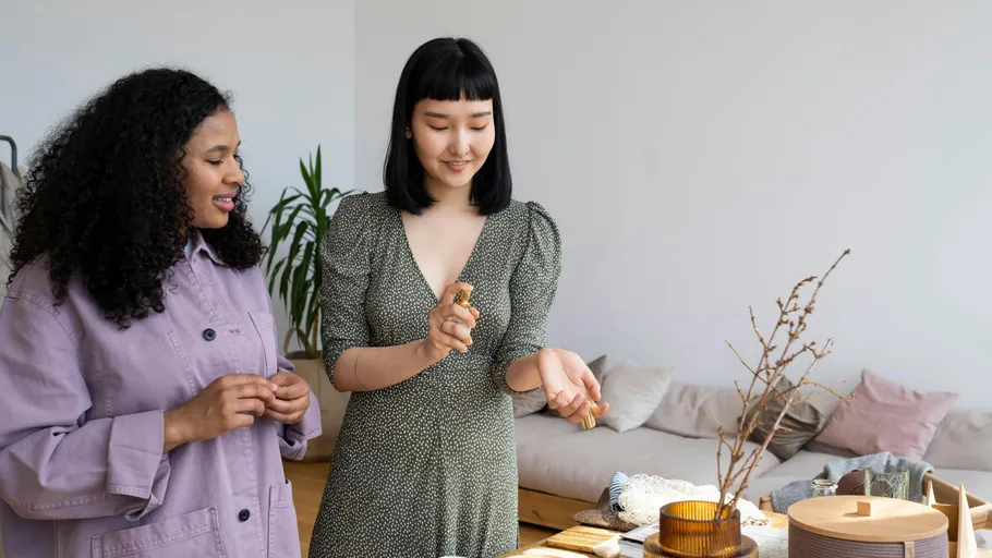 Zwei Frauen testen Parfüm im gemütlichen Wohnzimmer.