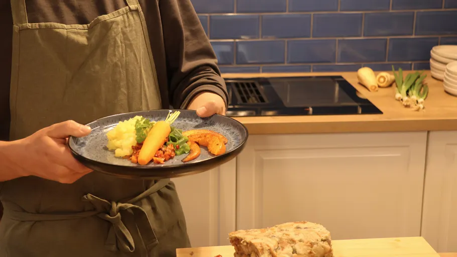 Person holding plate with colorful meal in kitchen.