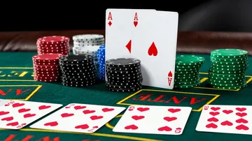 Pokerkarten und Chips auf grünem Tisch.
