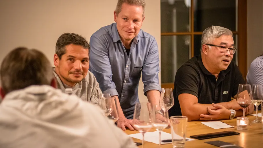 Three men sitting, talking at a table.