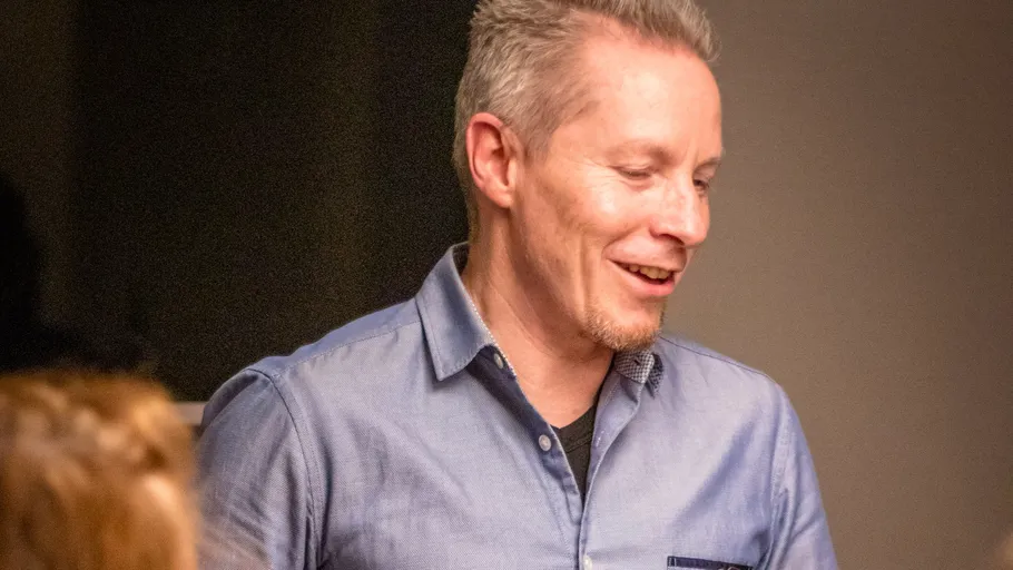 Man smiling wearing a blue shirt indoors.