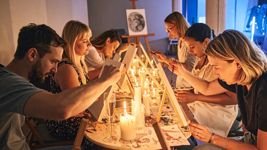 People painting with candles in warm studio.