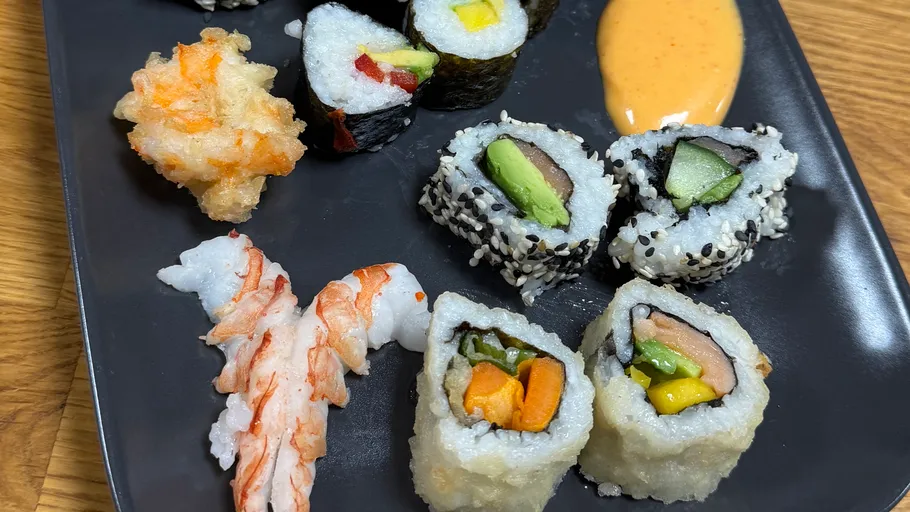 Verschiedene Sushi-Rollen auf einem schwarzen Teller.