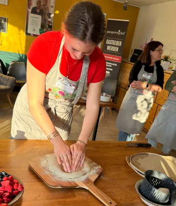 Woman kneading dough on wooden board indoors.