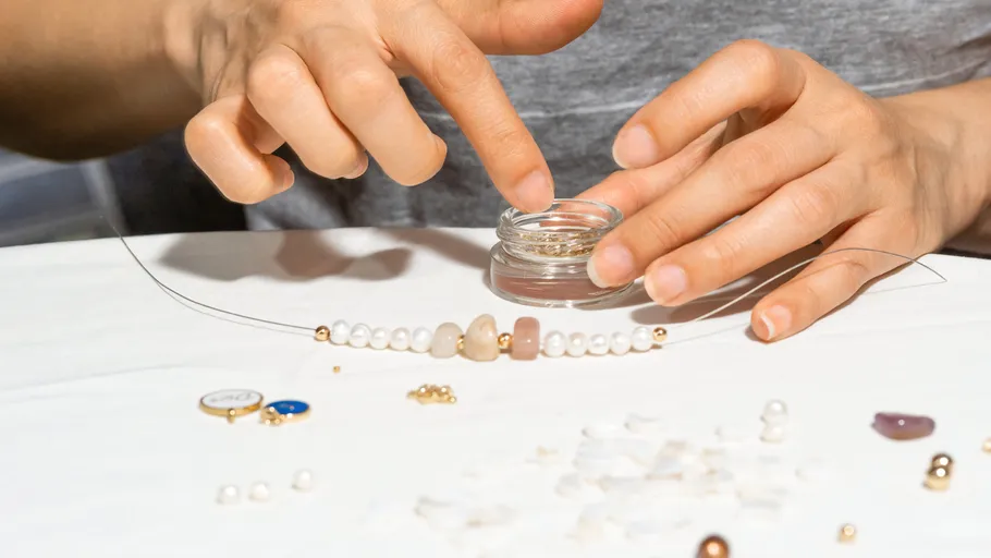 Hände erstellen Schmuck auf weißem Tisch.