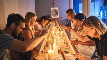 Group painting at candlelit table indoors.
