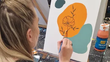 Person malt Blume auf Leinwand mit Acrylfarben.