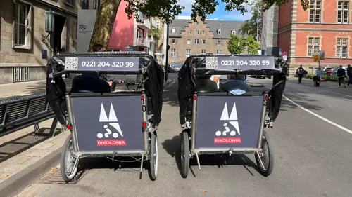 Two rickshaws parked on a city street.