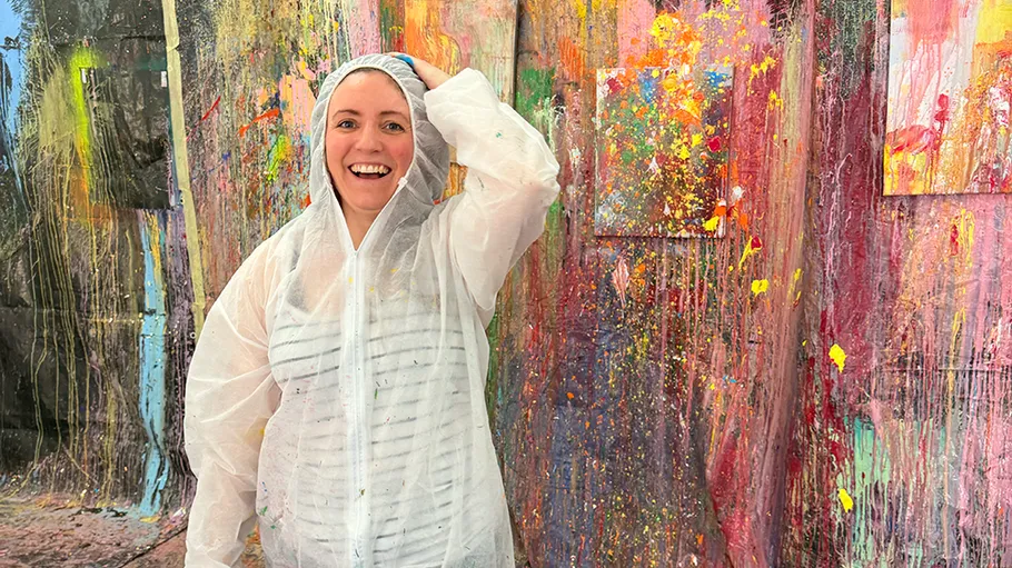 Person lächelt, trägt Schutzanzug im Kunststudio.