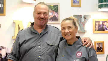 Zwei lächelnde Personen in Kochuniformen drinnen.